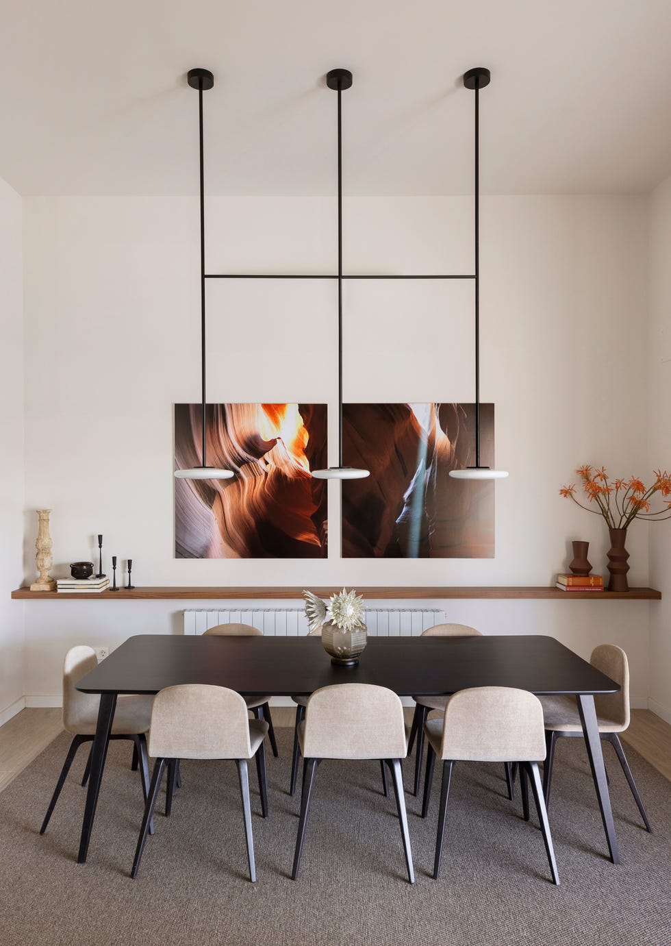 mesa de comedor de madera oscura con sillas tapizadas en beige, lámparas suspendidas y fotografías en la pared