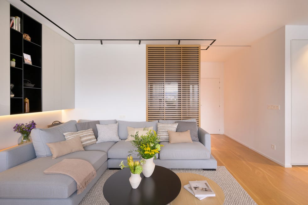 salón minimalista cálido con sofá rinconera gris y cerramiento de madera