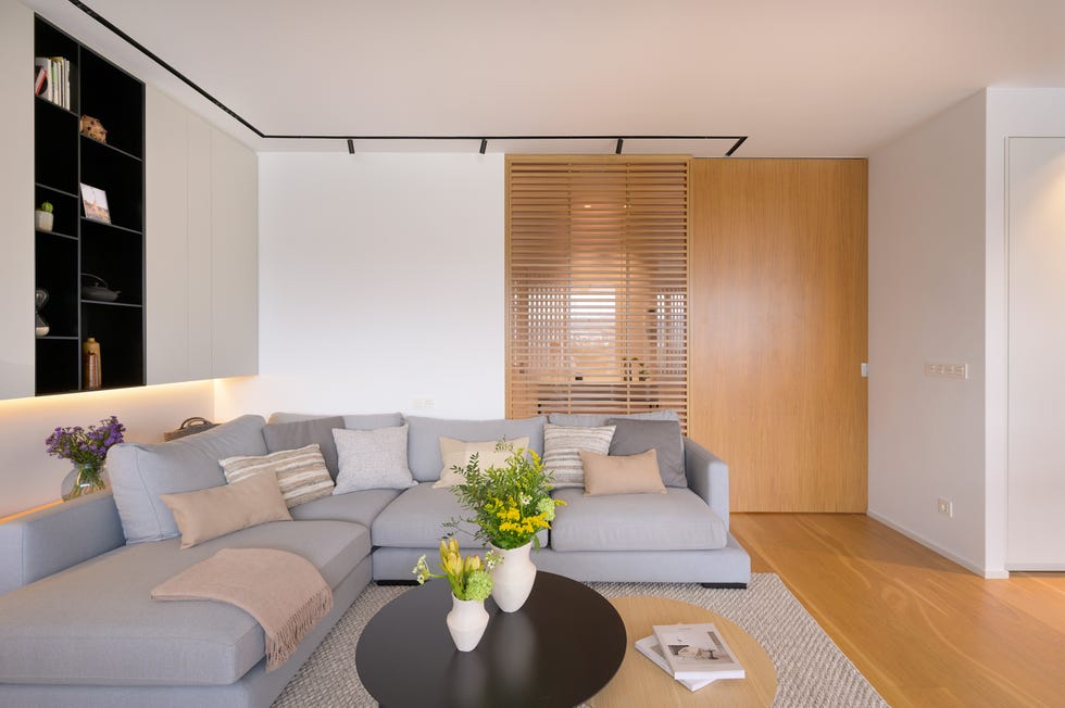salón minimalista cálido con sofá rinconera gris y cerramiento de madera