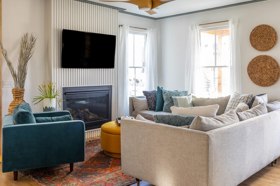 salón con sofá gris, butaca de terciopelo azul y puff amarillo