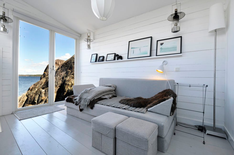 salón moderno con sofá y pufs grises con vistas al mar