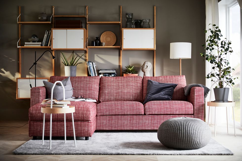 salón con sofá de color burdeos, mesa auxiliar y puf gris trenzado