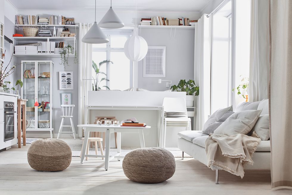 salón de estilo nórdico decorado en color blanco con dos pufs de fibras naturales