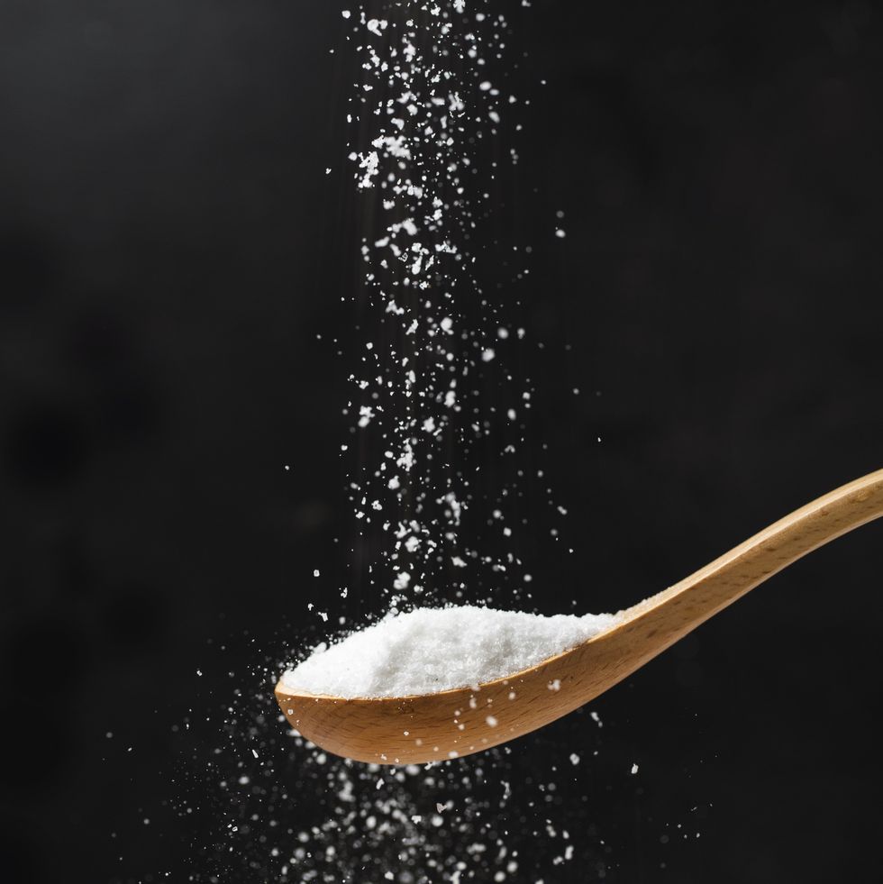 salt in wooden spoon on black background