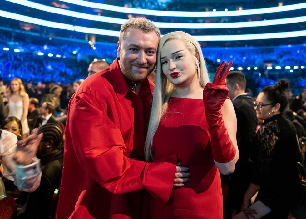 sam smith and ﻿kim petras wearing red and smiling for the camera, with a crowd behind them at the grammy awards ceremony
