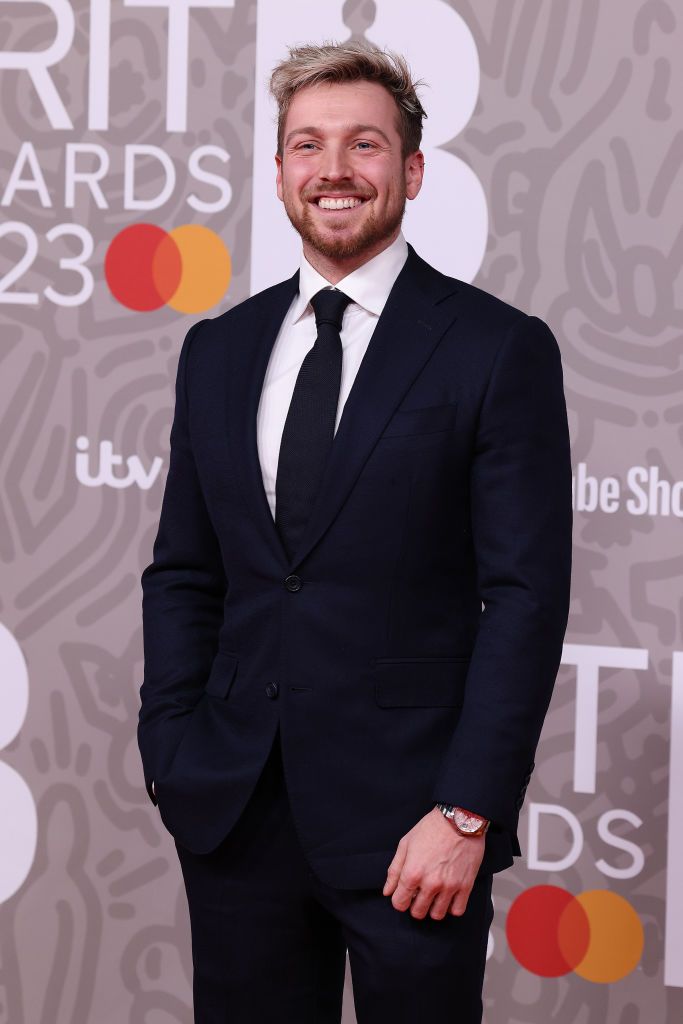 sam thompson attends the brit awards 2023 at the o2 arena on february 11, 2023 smiling on carpet as he wears smart black suit