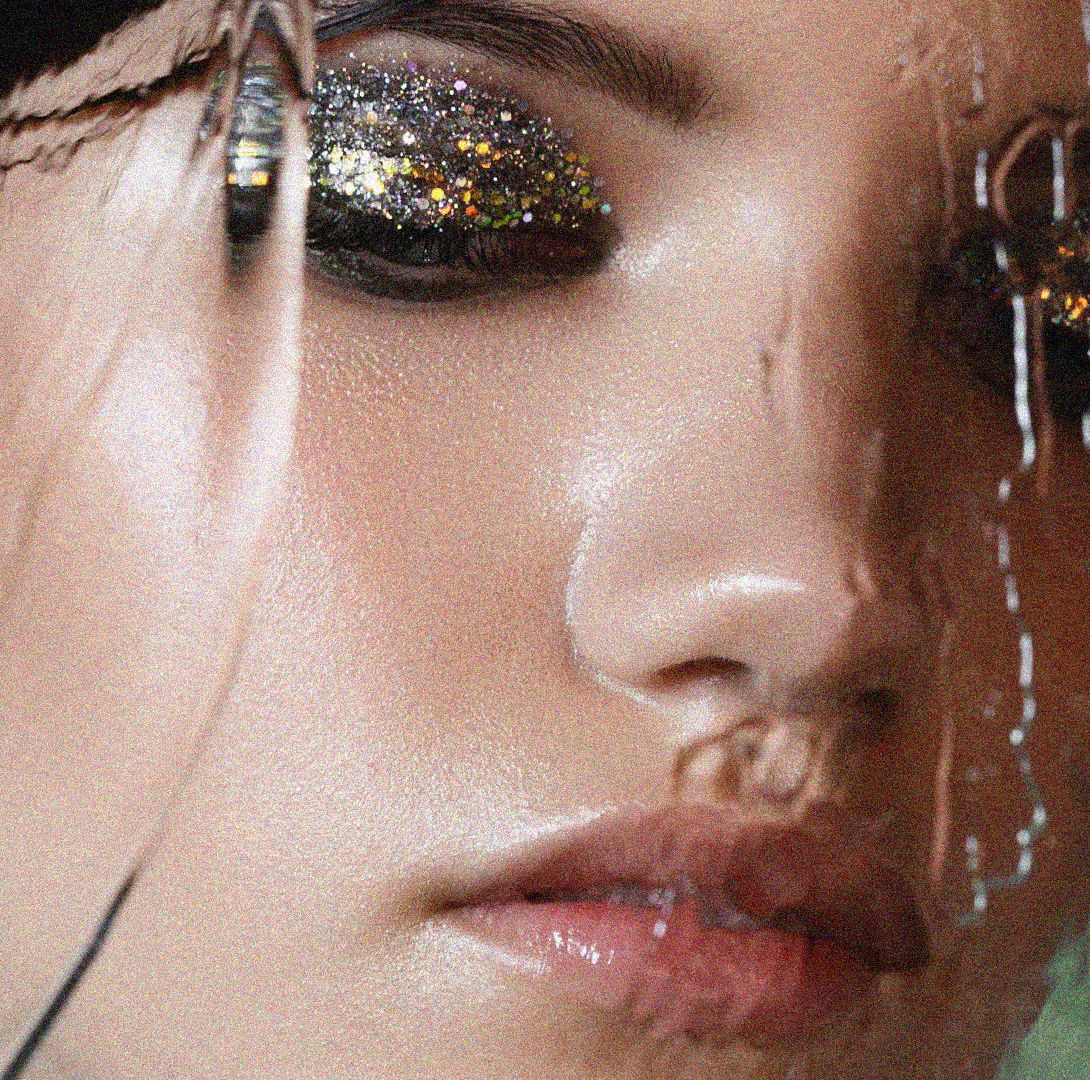 an abstract image of a woman with silver glittery eyeshadow looking blurred and downcast