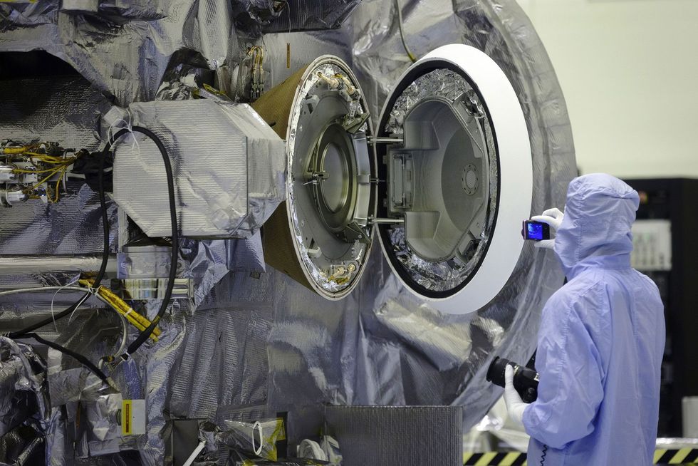 Op het Kennedy Space Center inspecteert een technicus tijdens het testen van het afdichtluik de geopende capsule waarin de bodemmonsters naar de aarde worden teruggebracht het cirkelvormige voorwerp rechts op de foto Het lekkende opvangfilter met het ruimtegruis werd in deze capsule geborgen om later naar de aarde te worden teruggebracht