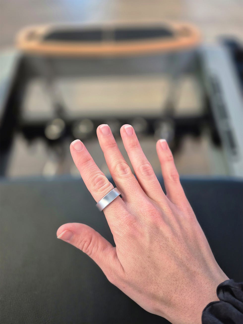 a hand wearing a silver smart ring