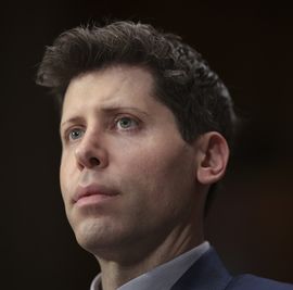 a man looks forward, he wears a suit jacket and collared shirt whose collars are just visible