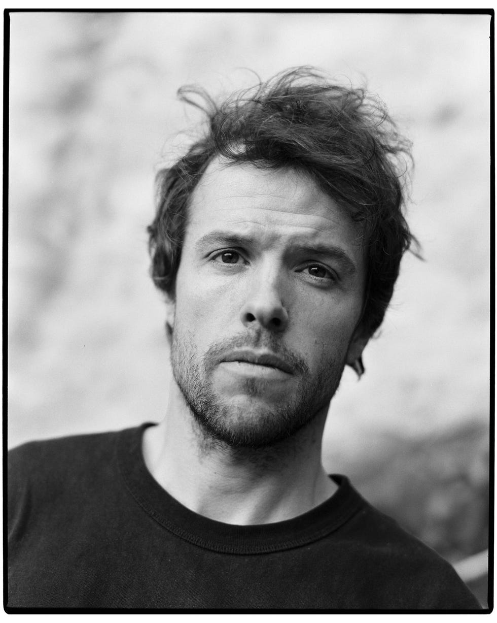 a black and white headshot of a man in a t shirt