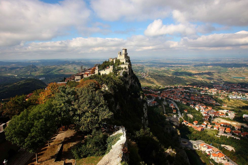 Met slechts 61 vierkante kilometer grondgebied is het piepkleine staatje San Marino gelegen op een rots die door het weidse Italiaanse landschap wordt omgeven