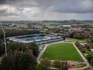 a large stadium with a field and trees around it