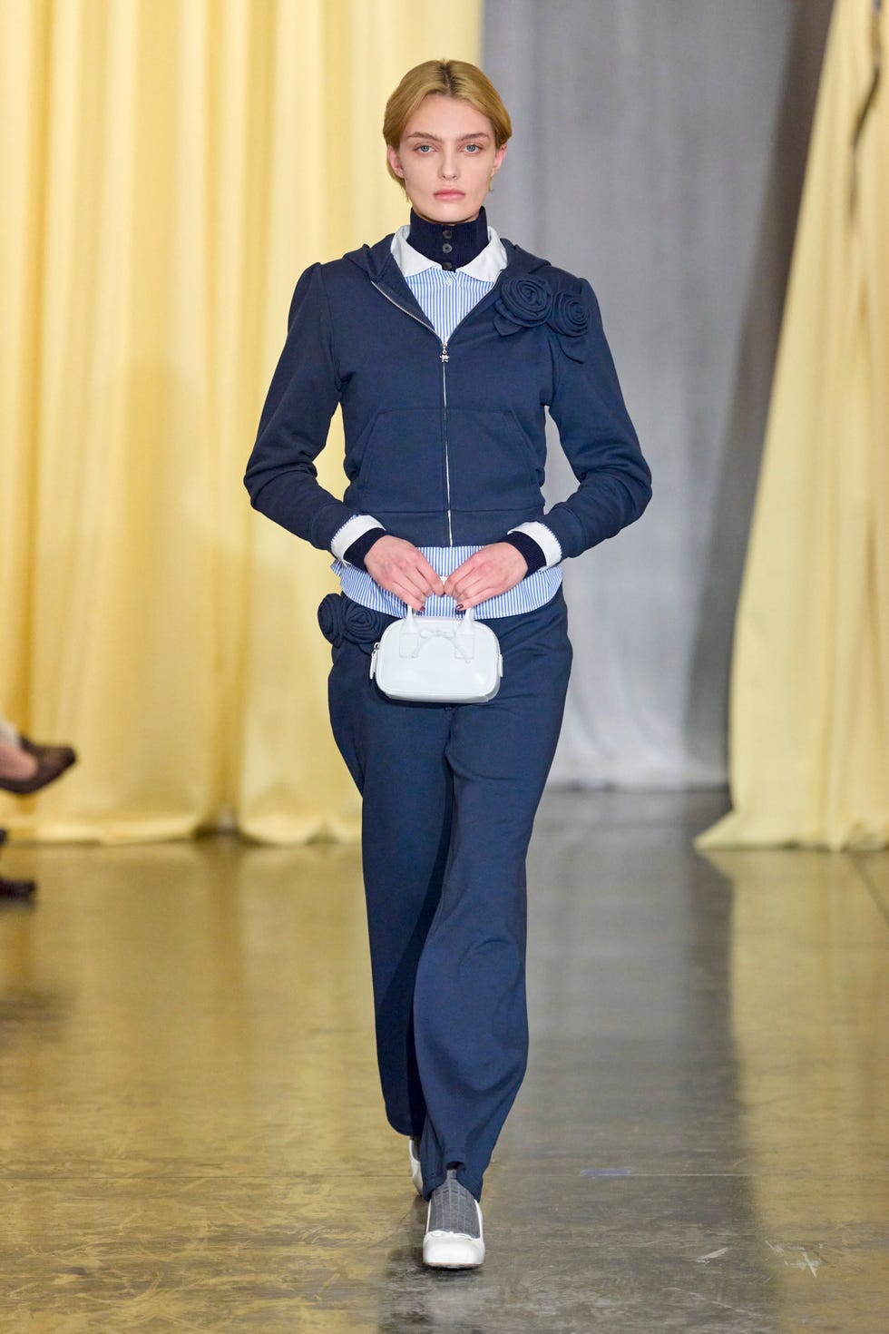a person wearing a blue coat and white shoes