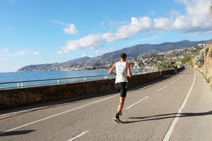 a man running on a road by a body of water