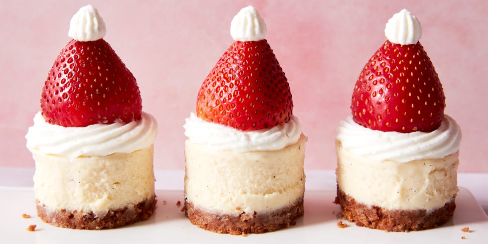 mini cheesecake bites topped with strawberries and whipped cream to look like a santa hat