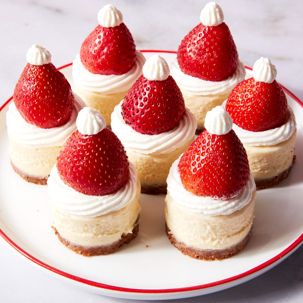 mini cheesecake bites topped with strawberries and whipped cream to look like a santa hat