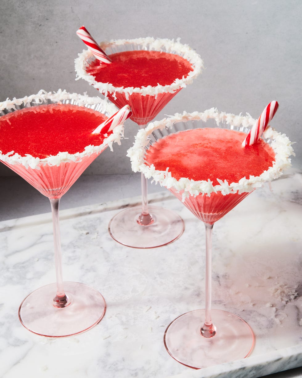 red cocktail with a coconut rim and peppermint stick garnish