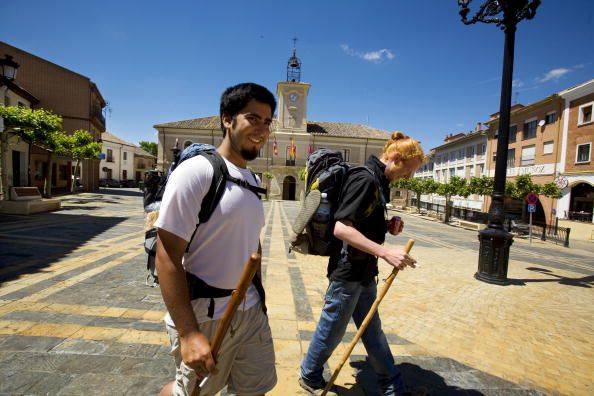 Santiago's Way. Jacobean Routes. French Way. Two pilgrims with their rucksacks and walking sticks at the Town Hall square in Carrion de los Condes, Palencia.The village is known by the Pantocrator of the church of Santiago, one of the symbols of Romanic s