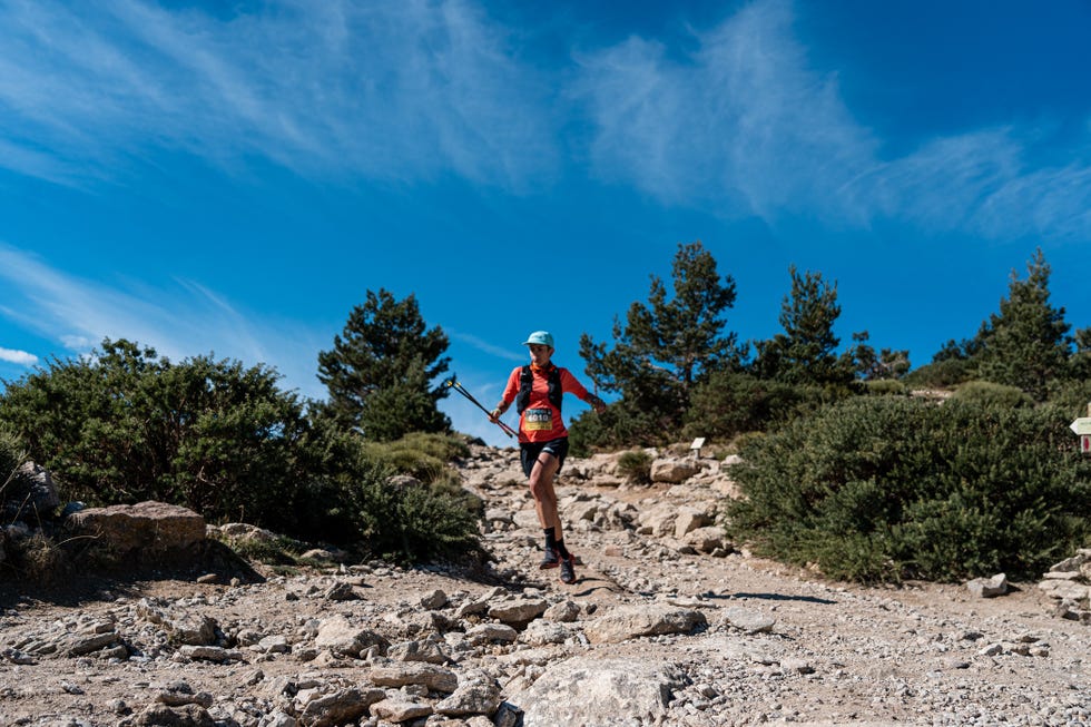 a trail runner navigating a rocky terrain under a clear blue sky