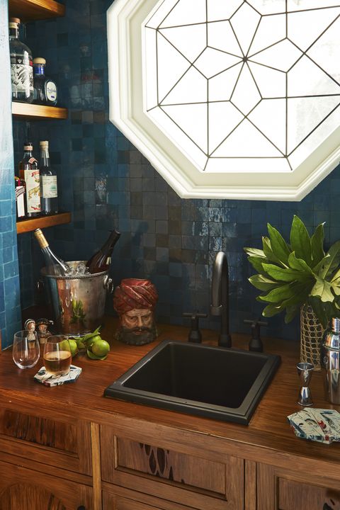 a leaded glass window filters light into a deep sea green butlers pantry