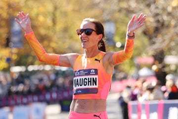 a runner raises her hands in celebration