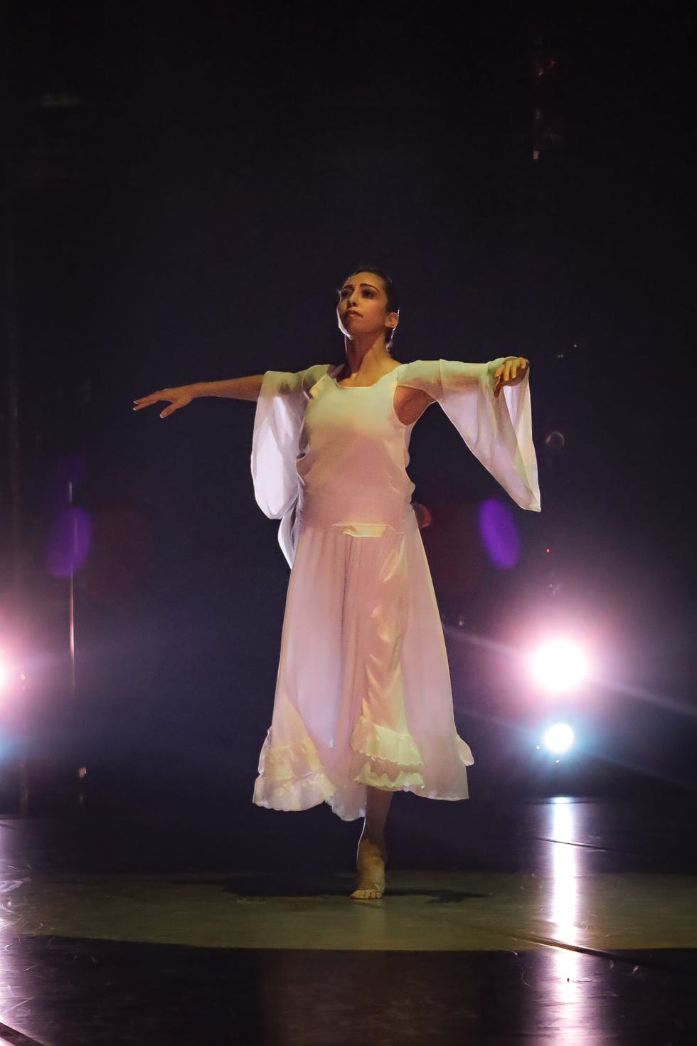 a dancer in a white dress performing on stage