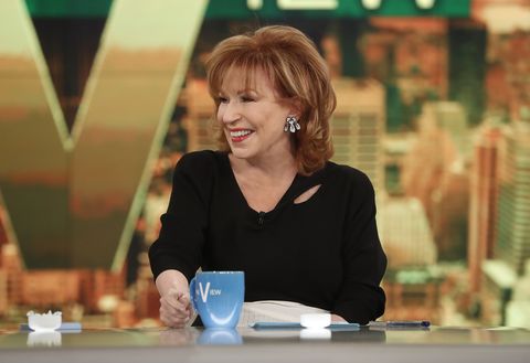 joy behar sitting at the hosting table of the view, smiling and looking off camera