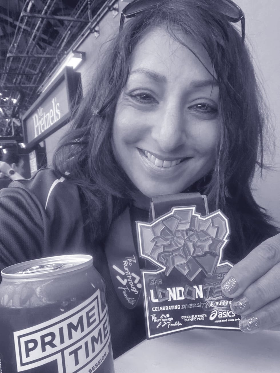 smiling runner wearing and holding a race medal