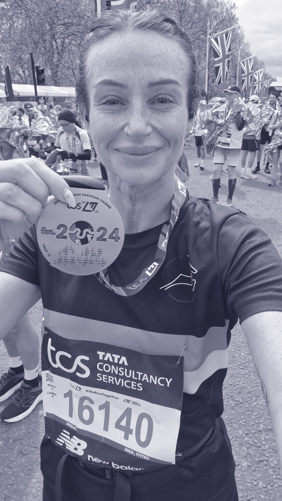 woman runner wearing a london marathon medal, having just completed the race