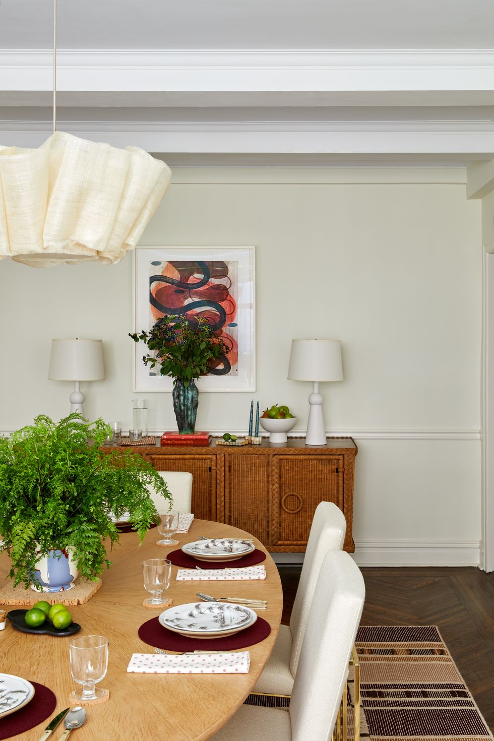 dining room table with place settings below a fabric light fixture