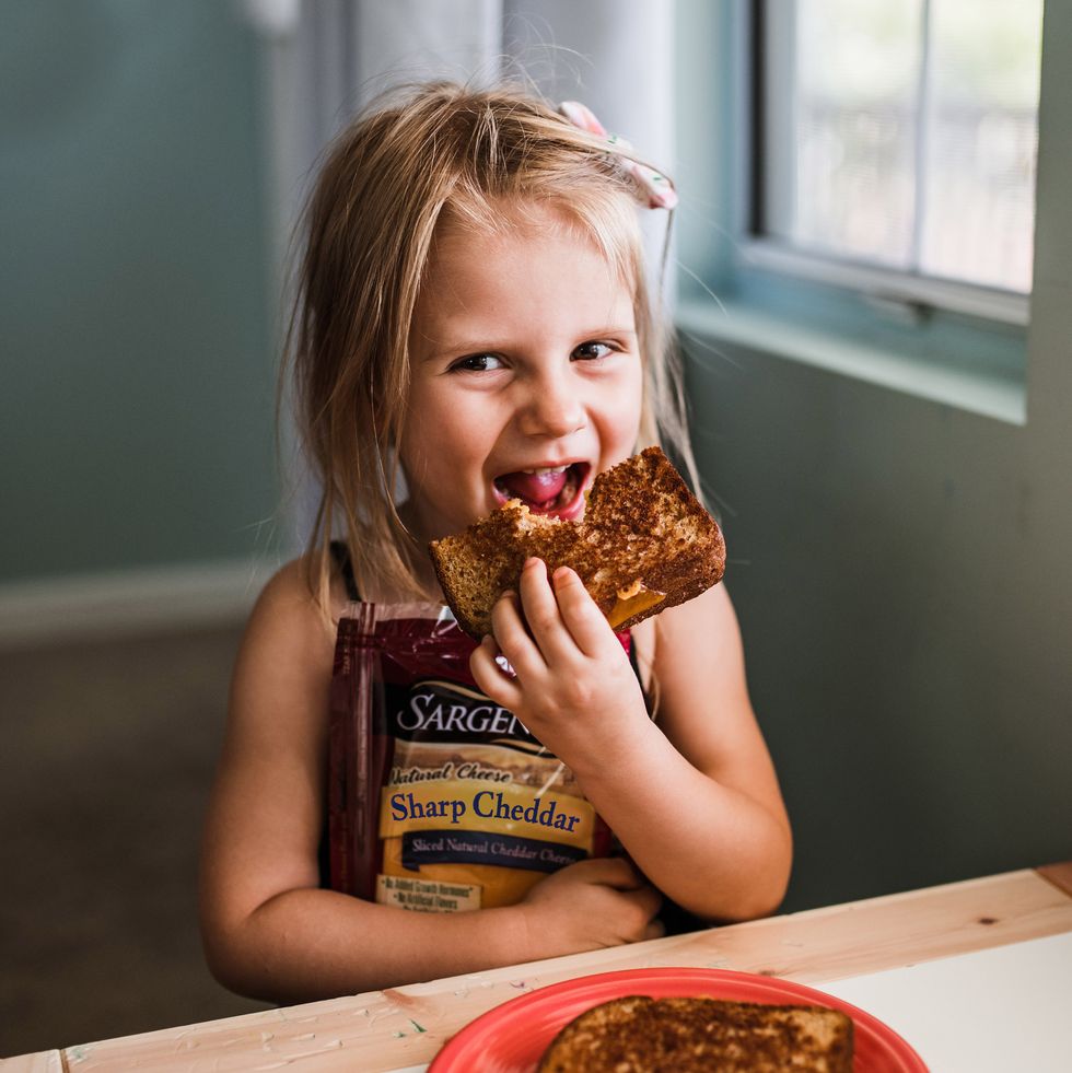 little girl eating grilled cheese made with sargento