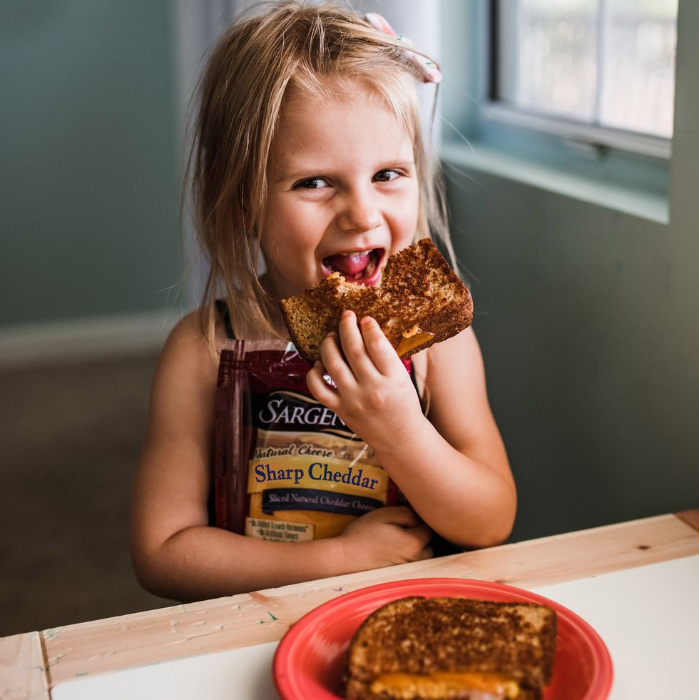 little girl eating grilled cheese made with sargento