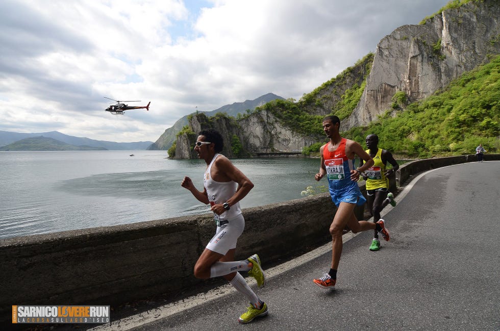 a group of people running on a road by a helicopter