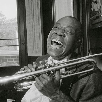 louis armstrong smling while holding his trumpet