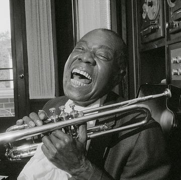 louis armstrong smling while holding his trumpet