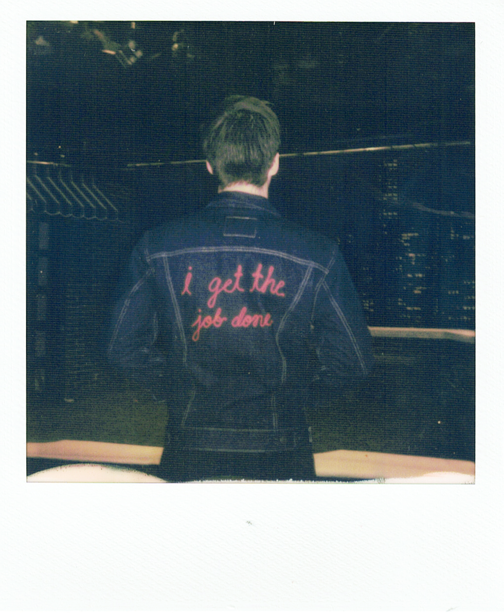 person wearing a denim jacket with a red embroidery slogan