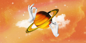 two manicured hands in black and white hold up the planet saturn in bright orange the background is a cloudy, starry orange and red sky