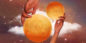 two hands hold up two orange planets in a dark, starry sky
