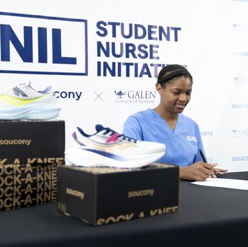 nurse signs paper at table with saucony shoes next to her