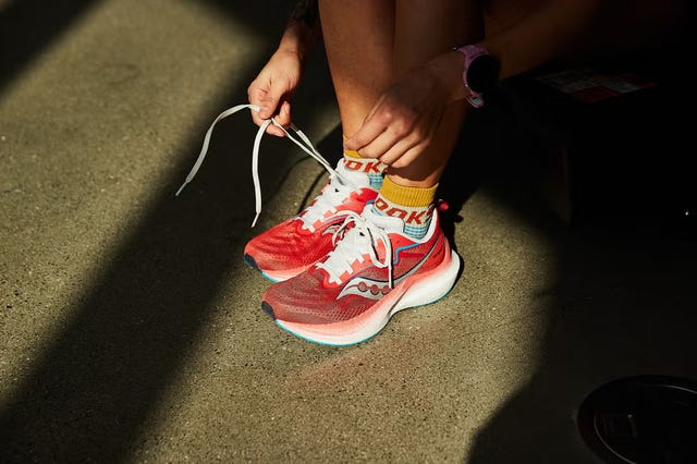 a person tying up a pair of red running shoes