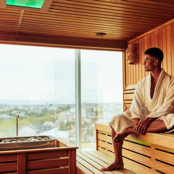a young african american man is wearing a bathrobe and enjoying the view of the city in the sauna