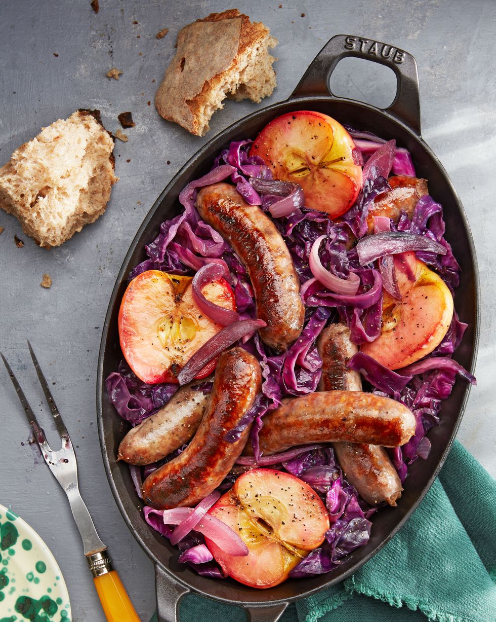 seared sausage with cabbage and pink lady apples in a cast iron pan with crusty bread