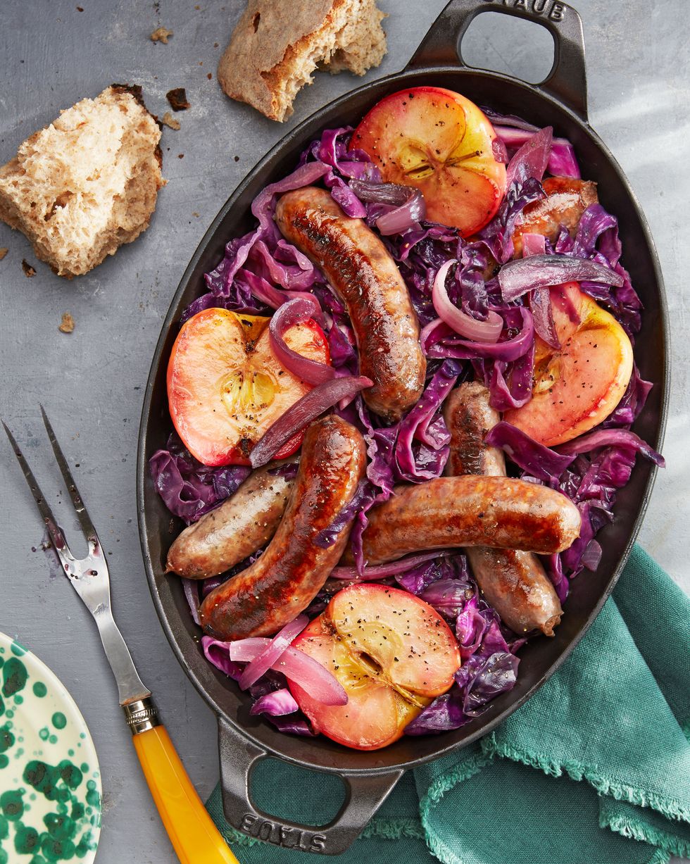 seared sausage with cabbage and pink lady apples in a cast iron pan with crusty bread