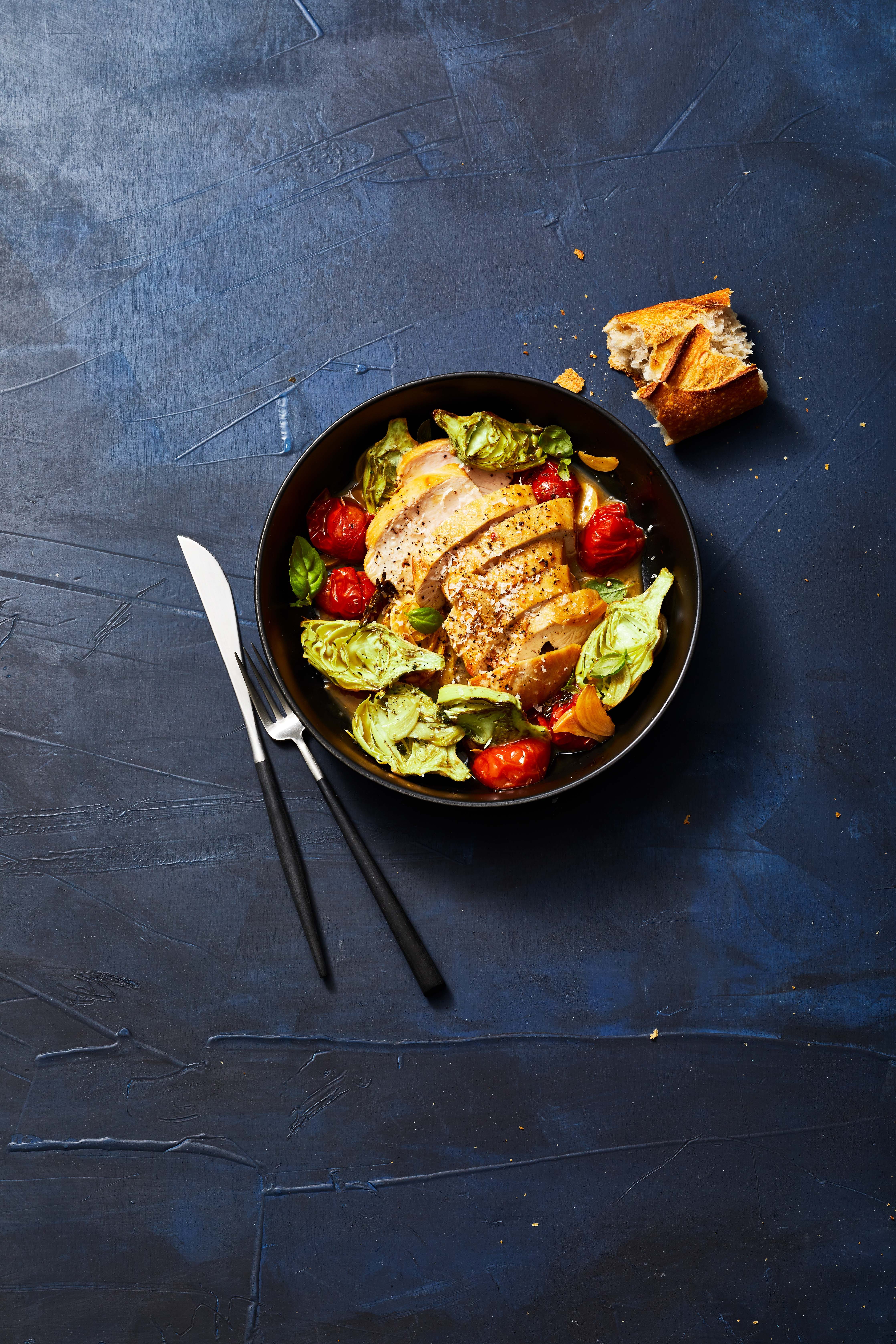 sautéed chicken and tomatoes with roasted artichokes in a bowl