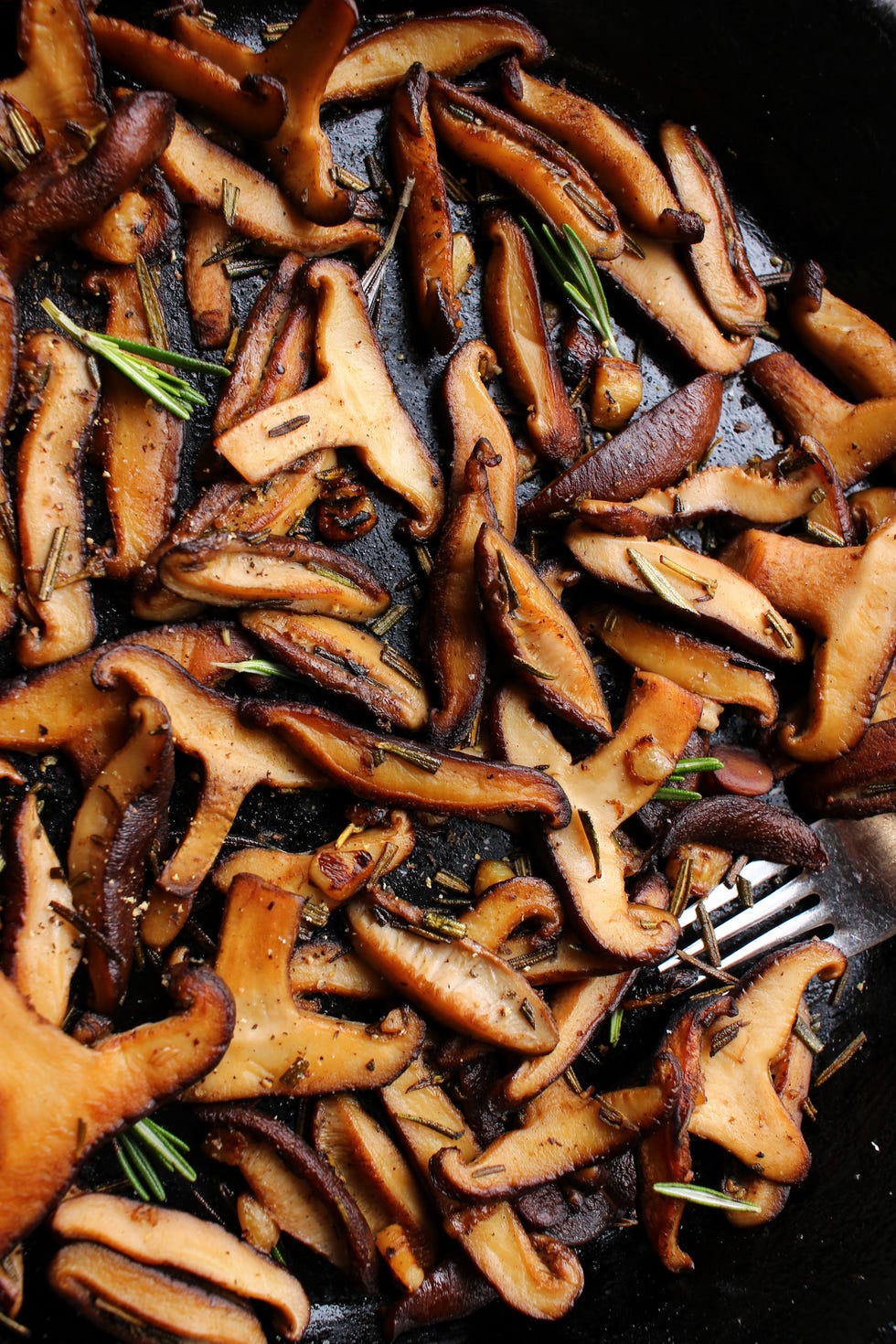 garlic rosemary sauteed mushrooms in a black cast iron skillet, buttered, salted, and peppered