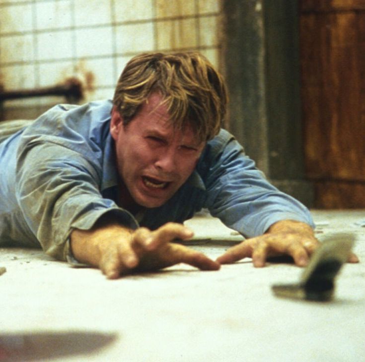 dr lawrence gordon reaches for his phone, just out of reach, in a scene from saw