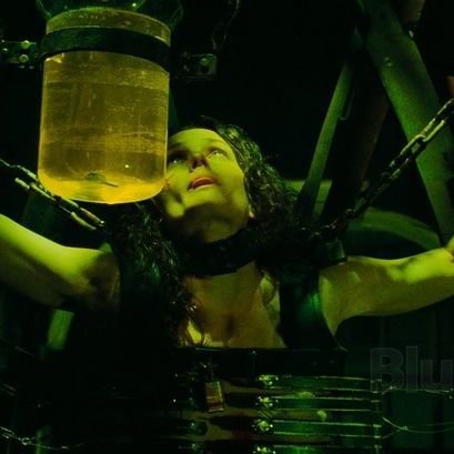 a woman is hanging, suspended in a jigsaw trap with a jar of liquid in front o f her in a scene from saw iii