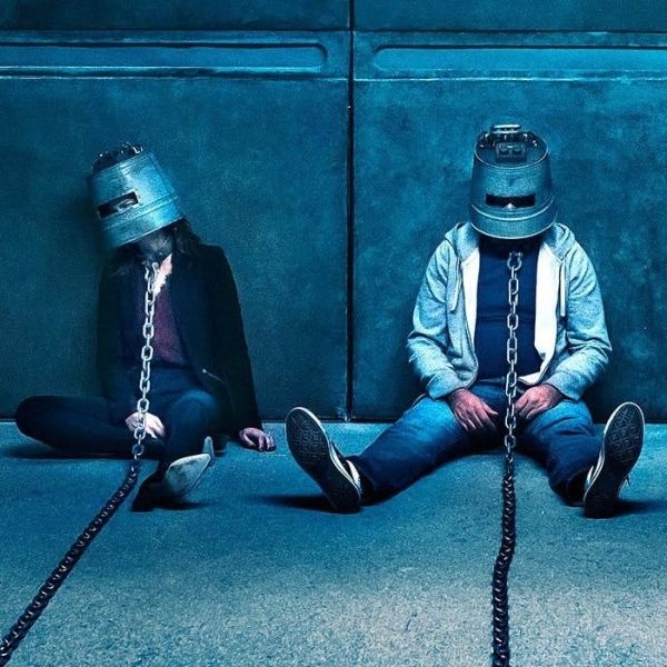 people are chained up with metal buckets on their heads in a scene from jigsaw