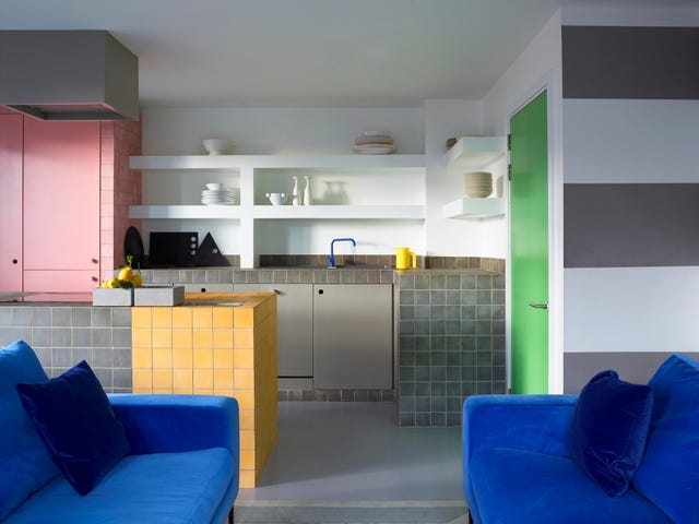 modern open plan kitchen with grey island and pastel doors and cabinets